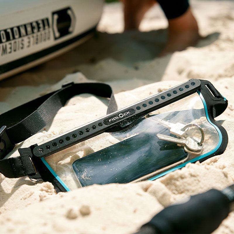 FIDLOCK-HERMETIC-sling-bag-transparent-outdoor-liegt-im-sand-gefüllt_800x800